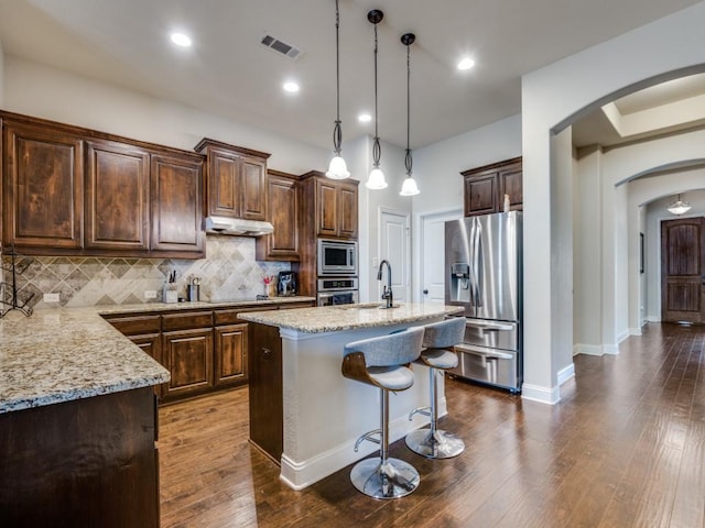 1314 Greenrock Ct, Midlothian, TX 76065 - kitchen featuring stainless steel appliances, arched walkways, light stone countertops, backsplash, and under cabinet range hood