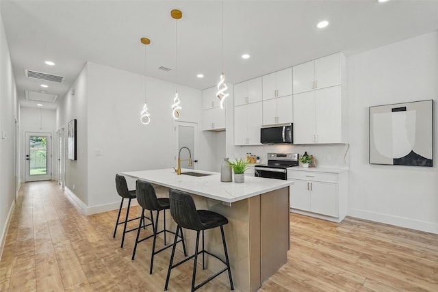 2910 Brigham Ln, Dallas, TX 75215 - kitchen featuring appliances with stainless steel finishes, light wood-style flooring, recessed lighting, a breakfast bar area, and a center island with sink