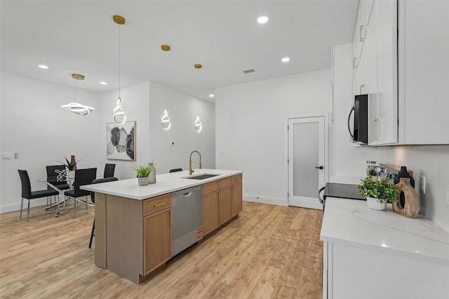 2910 Brigham Ln, Dallas, TX 75215 - kitchen featuring stainless steel appliances, light wood finished floors, an island with sink, recessed lighting, and pendant lighting
