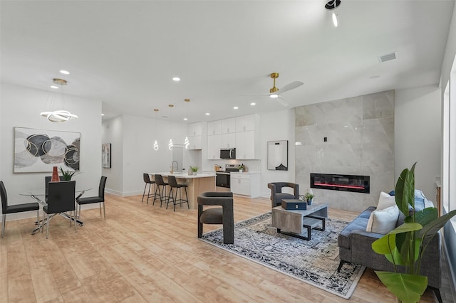 2910 Brigham Ln, Dallas, TX 75215 - living area with light wood-style flooring, recessed lighting, a tile fireplace, and a ceiling fan