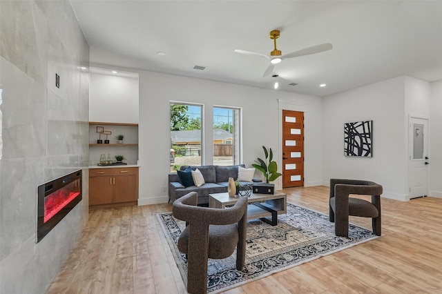 2910 Brigham Ln, Dallas, TX 75215 - living area with light wood-style flooring, a tile fireplace, a ceiling fan, and recessed lighting