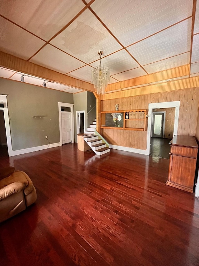 1612 Lagonda Ave, Fort Worth, TX 76164 - unfurnished living room featuring stairs, wooden walls, wood finished floors, and a chandelier