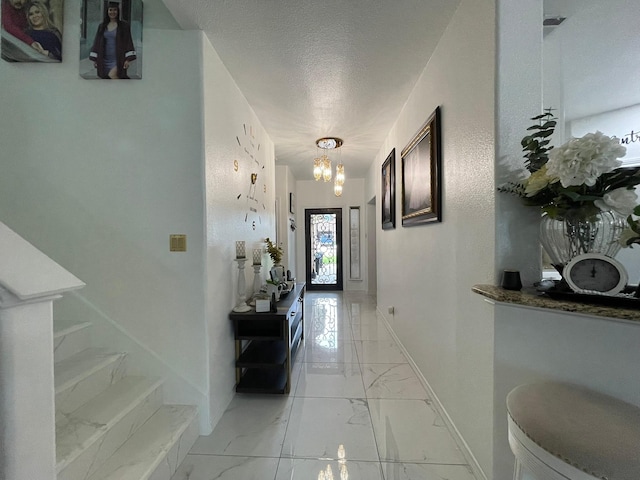 1603 Pacific Ave, Ennis, TX 75119 - corridor featuring light marble finish floors, a chandelier, a textured ceiling, and stairway