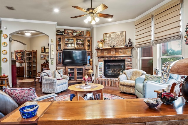 513 Hearth Ter, Argyle, TX 76226 - living room featuring arched walkways, wood finished floors, ceiling fan, crown molding, and a brick fireplace