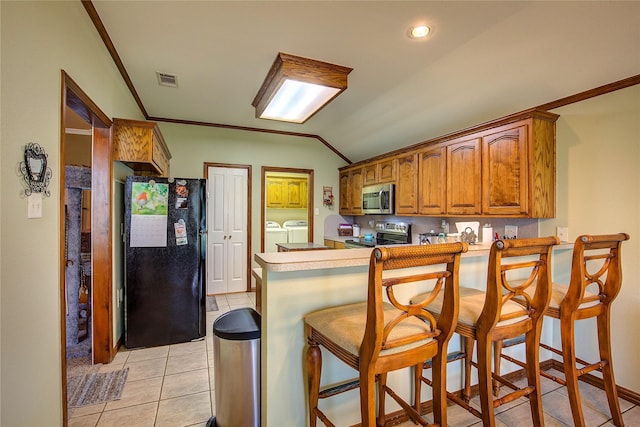 1813 Ranch Rd, Royse City, TX 75189 - kitchen featuring stainless steel appliances, washer and clothes dryer, a peninsula, light tile patterned floors, and brown cabinets