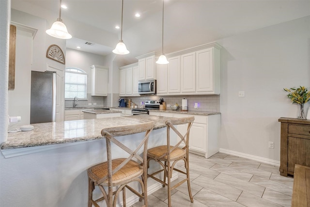 1148 Blue Sky Ln, Burleson, TX 76058 - kitchen featuring appliances with stainless steel finishes, tasteful backsplash, a peninsula, white cabinetry, and light stone counters