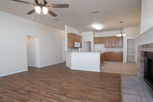 302 Howard Way Dr, Aledo, TX 76008 - kitchen with white microwave, wood finished floors, a fireplace, a ceiling fan, and open floor plan