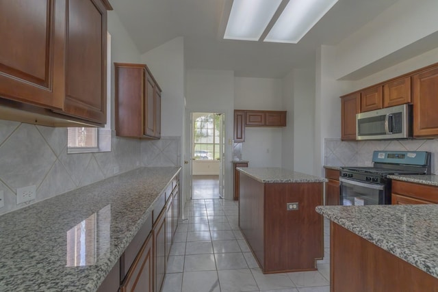 4600 Via Ventura, Mesquite, TX 75150 - kitchen featuring stainless steel microwave, gas range, light stone countertops, and a center island