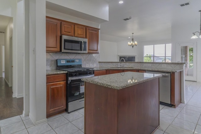4600 Via Ventura, Mesquite, TX 75150 - kitchen featuring stainless steel appliances, a peninsula, a chandelier, backsplash, and a center island
