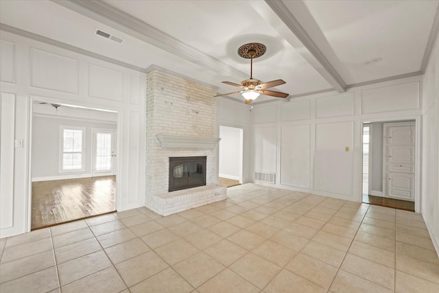 2205 Le Mans Dr, Carrollton, TX 75006 - unfurnished living room featuring a decorative wall, light tile patterned floors, a ceiling fan, a brick fireplace, and beamed ceiling