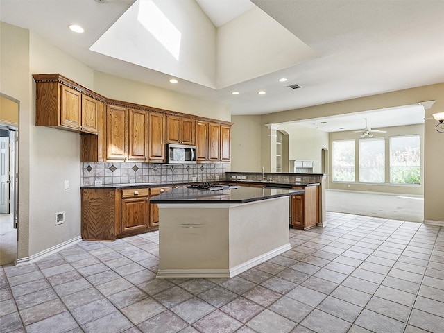 800 Rock Hill Rd, Prosper, TX 75078 - kitchen with stainless steel microwave, dark countertops, brown cabinets, ceiling fan, and tasteful backsplash