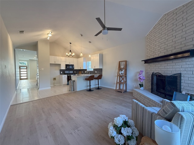 8525 Clearcreek Cir, Frisco, TX 75034 - living area featuring lofted ceiling, a chandelier, a ceiling fan, light wood-style floors, and a fireplace