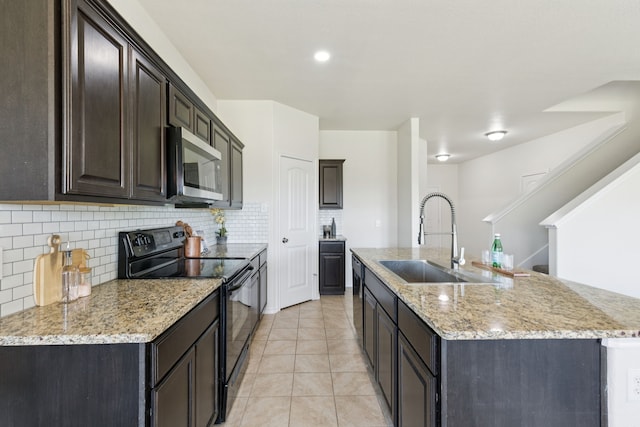 313 Pimlico Way, Ponder, TX 76259 - kitchen featuring black electric range, stainless steel microwave, backsplash, an island with sink, and light stone counters