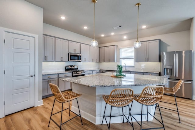 2521 Cobbler St, Northlake, TX 76247 - kitchen featuring appliances with stainless steel finishes, gray cabinets, a kitchen bar, light stone counters, and recessed lighting