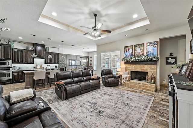 6513 Deer Horn Dr, Fort Worth, TX 76179 - living room with a tray ceiling, a ceiling fan, recessed lighting, a fireplace, and light wood finished floors