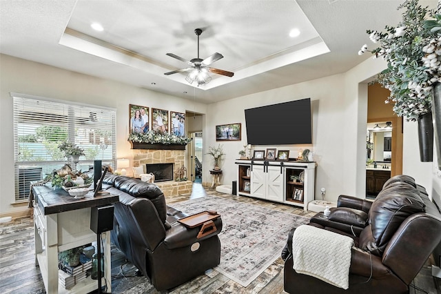6513 Deer Horn Dr, Fort Worth, TX 76179 - living area with a raised ceiling, wood finished floors, ceiling fan, a stone fireplace, and ornamental molding