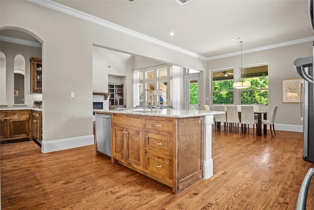 6901 Hickory Hill Cir, Argyle, TX 76226 - kitchen with stainless steel dishwasher, ornamental molding, light stone counters, wood finished floors, and a kitchen island with sink