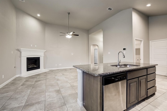601 Redding Dr, Saginaw, TX 76131 - kitchen with dishwasher, dark stone countertops, ceiling fan, a glass covered fireplace, and a center island with sink