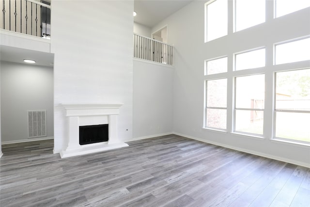 3620 Flintstone Dr, Plano, TX 75074 - unfurnished living room with a high ceiling, wood finished floors, healthy amount of natural light, and a fireplace with raised hearth