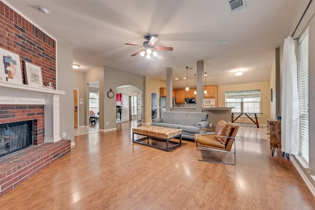 1306 Glendover Dr, Allen, TX 75013 - living area featuring a ceiling fan, arched walkways, light wood-style flooring, and a brick fireplace