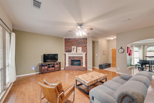 1306 Glendover Dr, Allen, TX 75013 - living area featuring light wood-style flooring, a ceiling fan, arched walkways, and a brick fireplace
