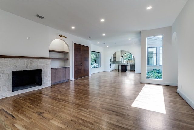 9701 Faircrest Dr, Dallas, TX 75238 - unfurnished living room with a fireplace, arched walkways, wood finished floors, and recessed lighting