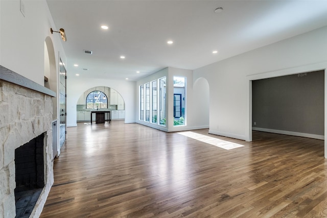 9701 Faircrest Dr, Dallas, TX 75238 - unfurnished living room with a stone fireplace, wood finished floors, recessed lighting, and arched walkways