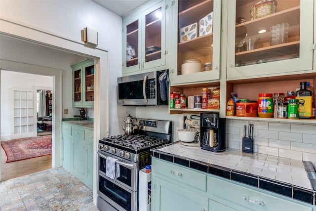 1320 Madeline Pl, Fort Worth, TX 76107 - kitchen with stainless steel appliances, tile counters, glass insert cabinets, and open shelves