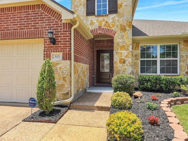 505 Peterhouse Dr, Mckinney, TX 75071 - view of exterior entry featuring stone siding, brick siding, a garage, and a shingled roof