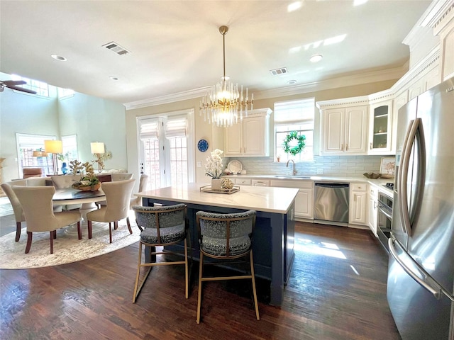 4716 Eva Pl, Plano, TX 75093 - kitchen featuring stainless steel appliances, plenty of natural light, a kitchen breakfast bar, tasteful backsplash, and ornamental molding