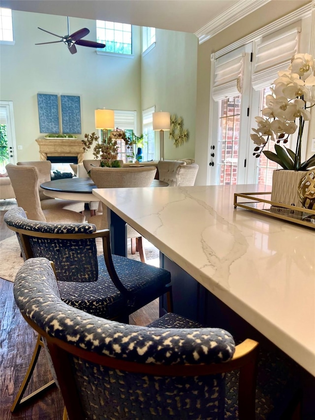 4716 Eva Pl, Plano, TX 75093 - dining space featuring ceiling fan, a fireplace, ornamental molding, wood finished floors, and a towering ceiling
