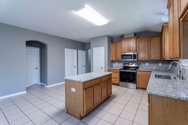 3106 Connor Ln, Wylie, TX 75098 - kitchen with appliances with stainless steel finishes, light tile patterned floors, a kitchen island, and arched walkways