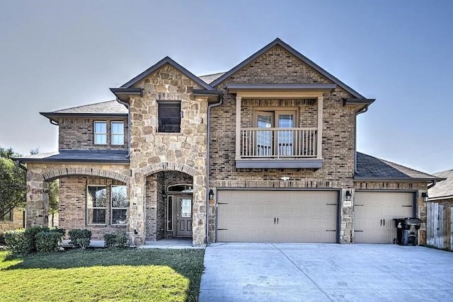 9207 Lake Pointe Dr, Temple, TX 76502 - french country home featuring concrete driveway, a balcony, a front yard, stone siding, and a garage