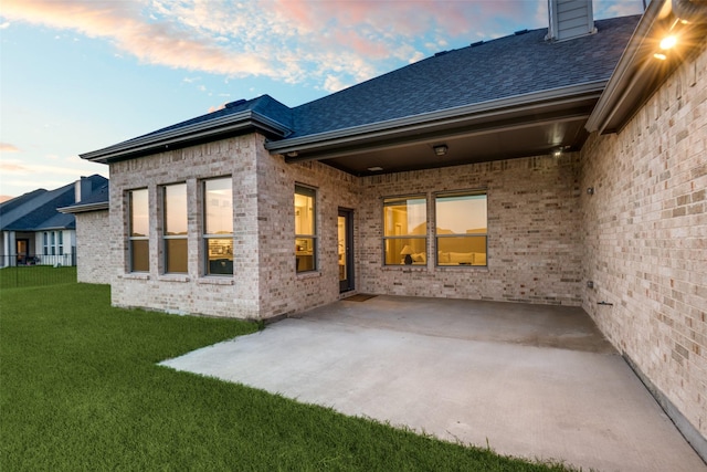 1301 Wilderness Ln, Forney, TX 75126 - back of house at dusk with brick siding, a lawn, a patio, and roof with shingles