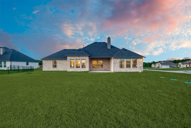 1301 Wilderness Ln, Forney, TX 75126 - back of house at dusk featuring a chimney, a patio, brick siding, and roof with shingles