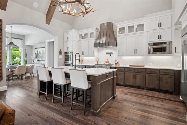 15111 Spider Lily Rd, Frisco, TX 75035 - kitchen with custom range hood, arched walkways, light countertops, tasteful backsplash, and high vaulted ceiling