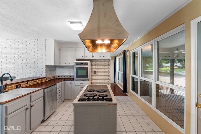858 River Rd, Shreveport, LA 71105 - kitchen with appliances with stainless steel finishes, island exhaust hood, backsplash, and light tile patterned flooring