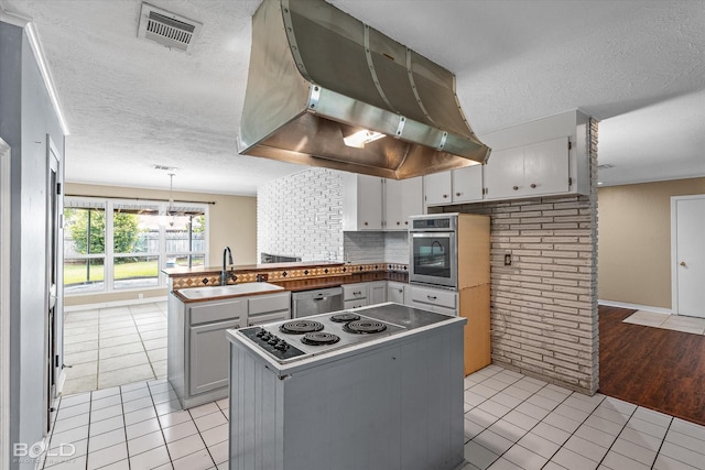 858 River Rd, Shreveport, LA 71105 - kitchen featuring exhaust hood, stainless steel appliances, a peninsula, light tile patterned flooring, and a textured ceiling