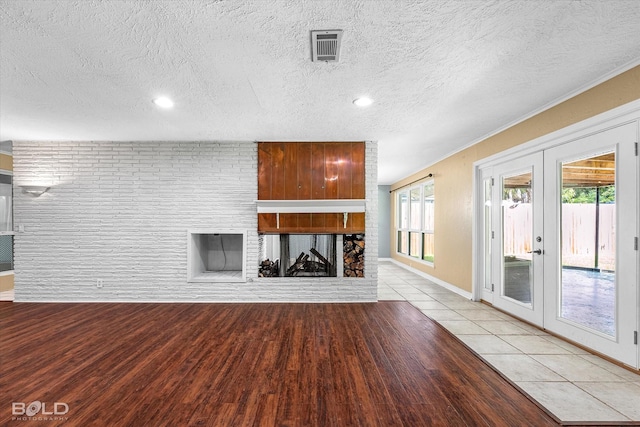 858 River Rd, Shreveport, LA 71105 - unfurnished living room with french doors, wood finished floors, a fireplace, a textured ceiling, and recessed lighting