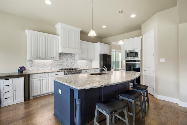 4618 Sky Harbor Dr, Rockwall, TX 75087 - kitchen featuring appliances with stainless steel finishes, tasteful backsplash, wood finished floors, a breakfast bar, and white cabinets