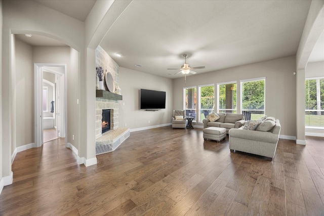 4618 Sky Harbor Dr, Rockwall, TX 75087 - living room featuring ceiling fan, a fireplace, dark wood-style flooring, and arched walkways