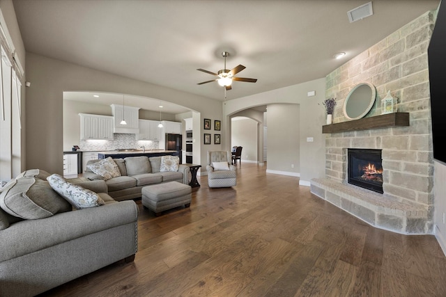 4618 Sky Harbor Dr, Rockwall, TX 75087 - living room featuring arched walkways, a ceiling fan, a stone fireplace, dark wood finished floors, and recessed lighting