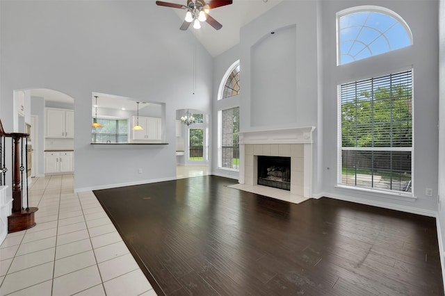 8504 Beatton Ct, Plano, TX 75025 - unfurnished living room featuring high vaulted ceiling, a tile fireplace, a ceiling fan, and light wood-style floors