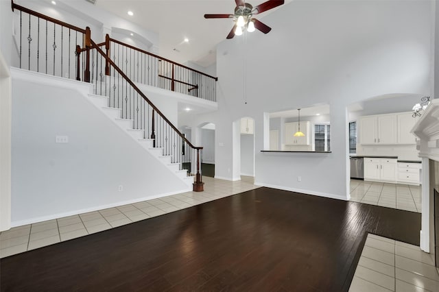 8504 Beatton Ct, Plano, TX 75025 - unfurnished living room with ceiling fan, arched walkways, light wood finished floors, a towering ceiling, and stairs