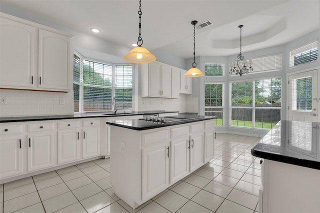 8504 Beatton Ct, Plano, TX 75025 - kitchen with black electric stovetop, dark countertops, a kitchen island, decorative backsplash, and a chandelier
