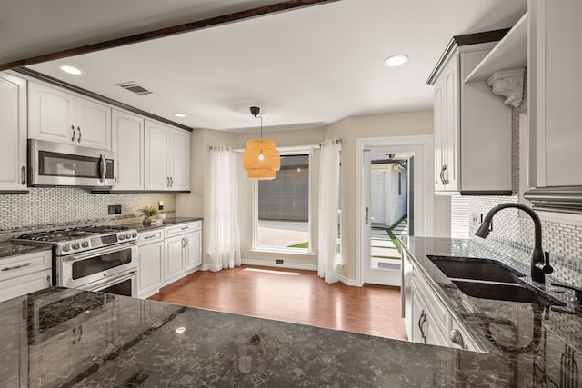 4147 Woodside Knl, Grapevine, TX 76051 - kitchen featuring stainless steel appliances, light wood-type flooring, decorative backsplash, dark stone counters, and plenty of natural light