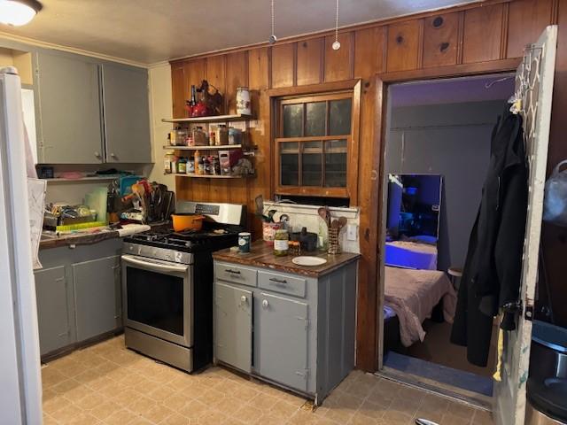 5829 Waddell St, Sansom Park, TX 76114 - kitchen with stainless steel range with gas cooktop, dark countertops, freestanding refrigerator, gray cabinetry, and open shelves