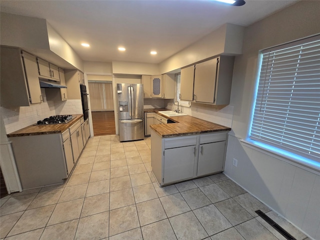 5323 Dazzle Dr, Dallas, TX 75232 - kitchen featuring stainless steel appliances, a peninsula, light tile patterned floors, and tasteful backsplash