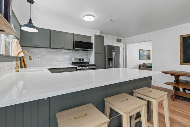 7516 Deaver Dr, North Richland Hills, TX 76180 - kitchen featuring appliances with stainless steel finishes, a peninsula, light wood-style floors, tasteful backsplash, and a kitchen bar