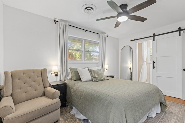 7516 Deaver Dr, North Richland Hills, TX 76180 - bedroom with a barn door, wood finished floors, and a ceiling fan